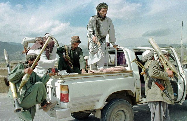 KABUL, AFGHANISTAN – OCTOBER 27: Taliban Muslim militia fighters scramble aboard their Toyota pickup carrying RPG-7 anti-tank rocket launchers and assault rifles 16 November. The Taliban's use of fast jeeps which revolutionised the Afghan battlefield, was a prime factor in their surprrise capture of the Afghan capital Kabul on 27 September. (Photo credit should read…