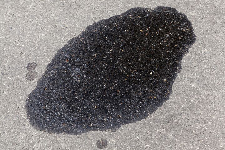 photography close-up of the asphalt road, which leaked old black oil from the car