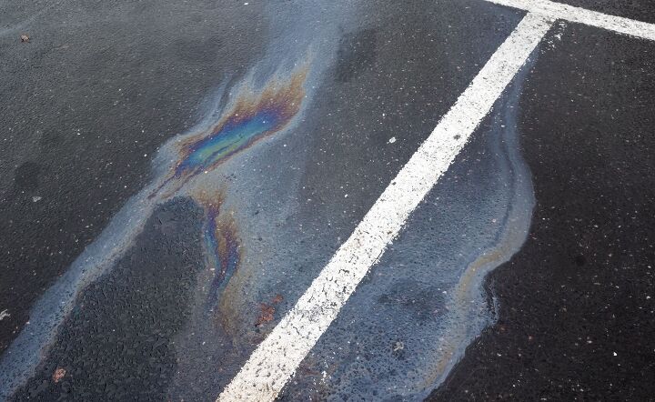 Oil spill on dark asphalt parking lot with dividing lines