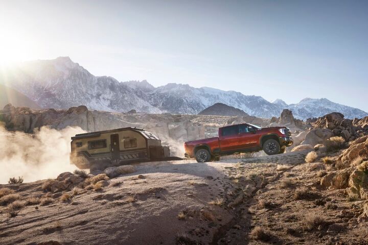 2024 GMC Sierra 2500HD AT4X towing a trailer through rocky mountain terrain.