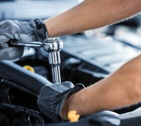 Close Up Shot of a Professional Mechanic Working on Vehicle in Car Service. Engine Specialist Fixing Motor. Repairman is Wearing Gloves and Using a Ratchet. Modern Clean Workshop.